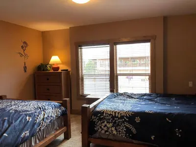a bedroom with two beds and a dresser and a window at Lakefront Townhouse Family Complex, Popular Wine Country and the Best Golfing in Osoyoos