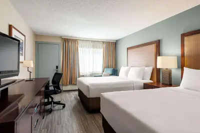 a hotel room with two beds and a flat screen tv at Travelodge by Wyndham Calgary South in Calgary