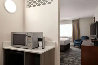 a hotel room with a microwave and a living room at Travelodge by Wyndham Calgary South in Calgary