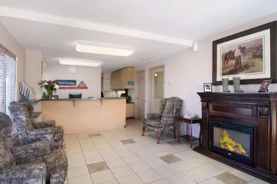 a living room with a fireplace and a kitchen at Travelodge by Wyndham Calgary South in Calgary