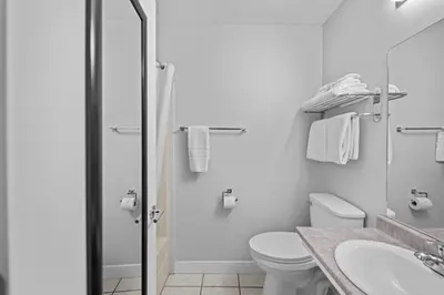 a white bathroom with a toilet and a sink at The Vista Inn in Kamloops