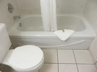 a white bathroom with a toilet and a bath tub at Super 8 by Wyndham Abbotsford BC in Abbotsford