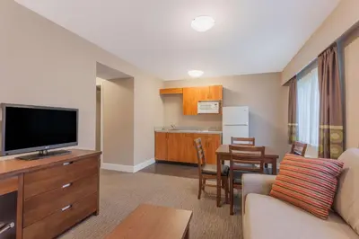 a living room with a couch and a tv and a kitchen at Super 8 by Wyndham Abbotsford BC in Abbotsford