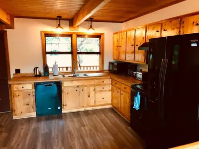 a kitchen with wooden cabinets and a black refrigerator at Brown's Bay Resort in Campbell River