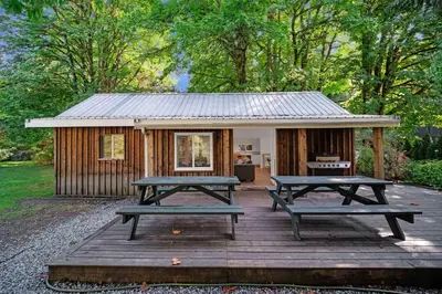 a cabin with two picnic tables in front of it at Sunwolf Riverside Cabins in Brackendale