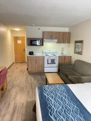 a hotel room with a bed and a couch and a kitchen at Rodeway Inn in Edson