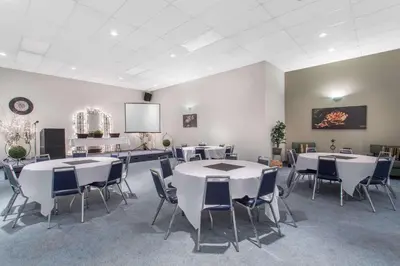 a conference room with tables and chairs and a screen at Ramada by Wyndham Williams Lake in Williams Lake