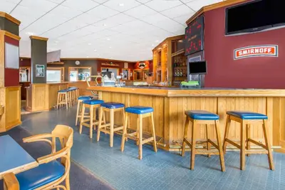 a restaurant with a bar with blue stools at Ramada by Wyndham Williams Lake in Williams Lake