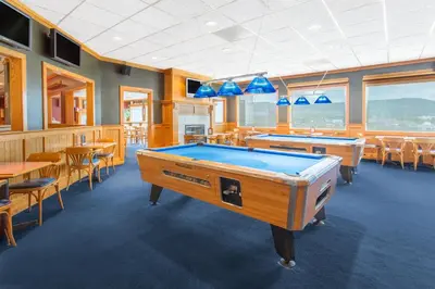 a room with a pool table and tables and chairs at Ramada by Wyndham Williams Lake in Williams Lake
