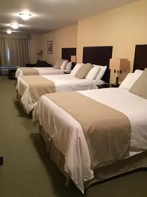 a row of four beds in a hotel room at Ramada by Wyndham Williams Lake in Williams Lake