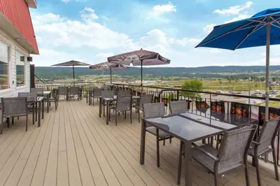 a deck with tables and chairs and umbrellas at Ramada by Wyndham Williams Lake in Williams Lake