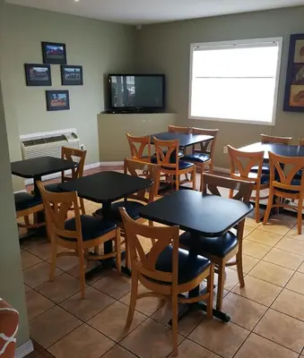 a dining room with tables and chairs and a tv at Grand Forks Inn in Grand Forks