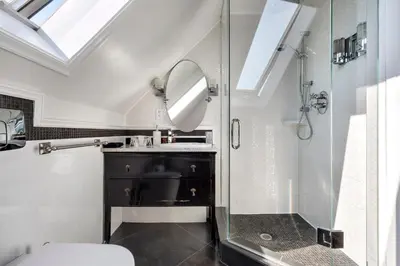 a bathroom with a shower and a toilet and a mirror at The Ivy on Parker Guest House in Vancouver