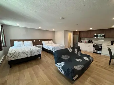 a bedroom with two beds and a couch and a kitchen at Western Traveller Motel in Grand Forks