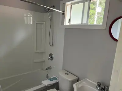 a white bathroom with a tub and a toilet and a sink at Pioneer Inn by the River in Port Hardy