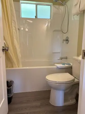 a white bathroom with a toilet and a bath tub at Pioneer Inn by the River in Port Hardy