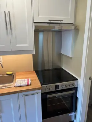 a kitchen with a stove and white cabinets at Pioneer Inn by the River in Port Hardy