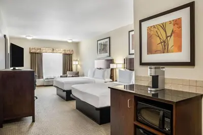 a hotel room with two beds and a television at Ramada by Wyndham Lac La Biche in Lac La Biche
