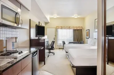 a hotel room with a bed and a kitchen at Ramada by Wyndham Lac La Biche in Lac La Biche