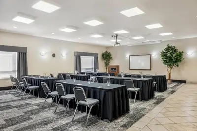 a conference room with tables and chairs and a screen at Ramada by Wyndham Lac La Biche in Lac La Biche