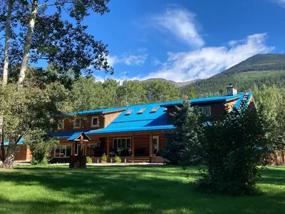 a large wooden house with a blue roof at Cougar Mountain Lodge and Resort Cabin Rentals in Valemount