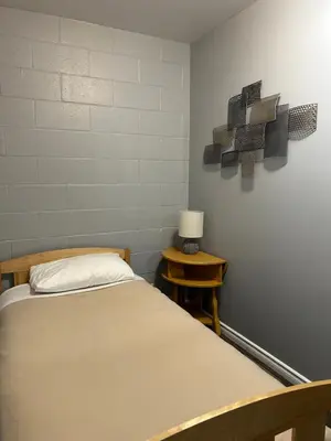 a room with a bed and a table with a lamp at Arrow Lake Motel in Fauquier