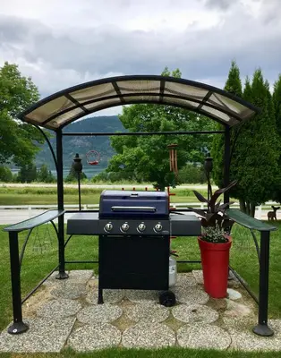 a grill under a pergola in a park at Arrow Lake Motel in Fauquier