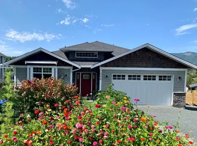 a house with a red door and some flowers at Valley View in Lake Cowichan