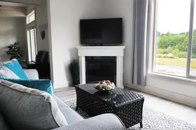 a living room with a fireplace and a tv on a mantel at Valley View in Lake Cowichan