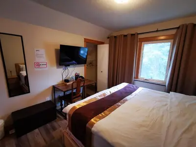 a bedroom with a bed and a television and a window at Riverfront Estate Bed&Breakfast Banff in Banff