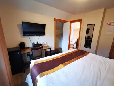 a hotel room with a bed and a desk and a television at Riverfront Estate Bed&Breakfast Banff in Banff