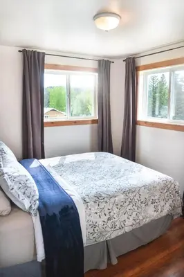 a bedroom with a bed and two windows at Willow Grove B&B Inn in Horsefly