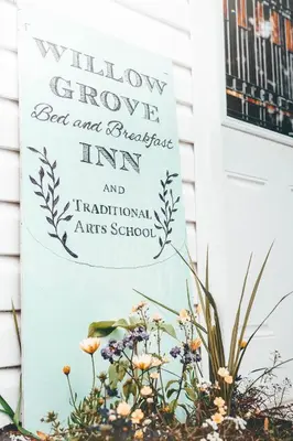 a sign in front of a door with flowers at Willow Grove B&B Inn in Horsefly