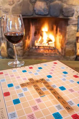 a glass of wine sitting next to a table with a chessboard and a fireplace at Storm Mountain Lodge & Cabins in Banff