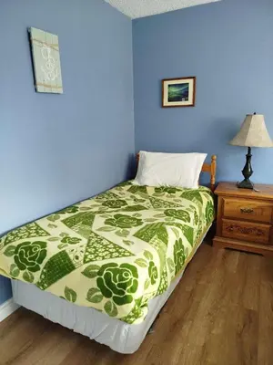 a bedroom with a bed with a green and white comforter at Jenny Guest House in Yellowknife