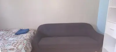 a brown couch sitting next to a bed in a room at Jenny Guest House in Yellowknife