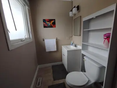 a bathroom with a toilet and a sink and a window at Jenny Guest House in Yellowknife