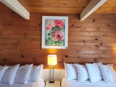 a bedroom with wooden walls and a bed with white pillows at Pines Motel in Sicamous