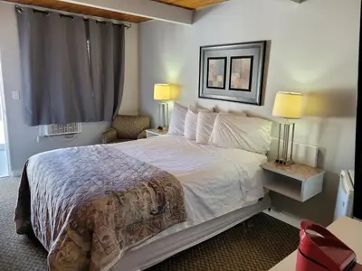 a bedroom with a bed and two lamps and a window at Pines Motel in Sicamous