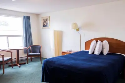 a hotel room with a bed and a table and a window at Prince Motel in Prince George