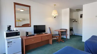 a hotel room with a desk with a television and a table at Prince Motel in Prince George