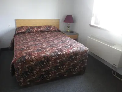 a bedroom with a bed with a blanket on it at Alcan Motor Inn in Haines Junction