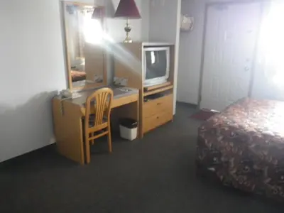 a hotel room with a bed and a desk with a television at Alcan Motor Inn in Haines Junction