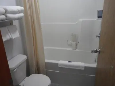 a bathroom with a white toilet and a bath tub at Alcan Motor Inn in Haines Junction