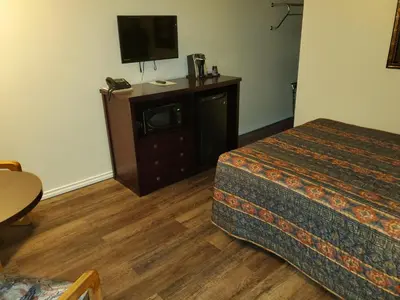 a hotel room with a bed and a flat screen tv at Battlefords Inn in North Battleford