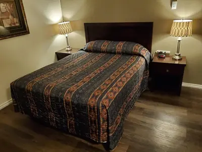 a hotel room with a bed and two lamps at Battlefords Inn in North Battleford