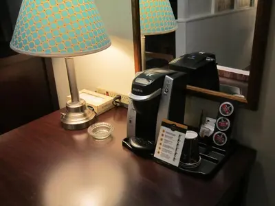 a coffee maker on a table with a lamp and a coffee machine at Battlefords Inn in North Battleford