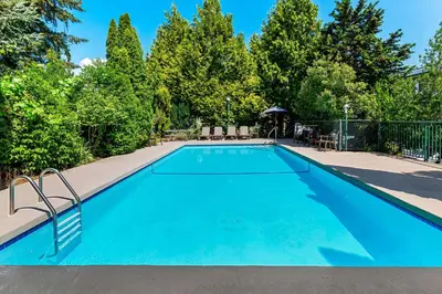 a blue swimming pool with chairs and trees at Best Western Cowichan Valley Inn in Duncan
