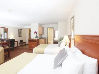 a hotel room with two beds and a desk at Stonebridge Hotel Dawson Creek in Dawson Creek