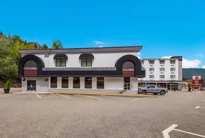 a white building with a car parked in a parking lot at Best Western Plus Columbia River Hotel in Trail